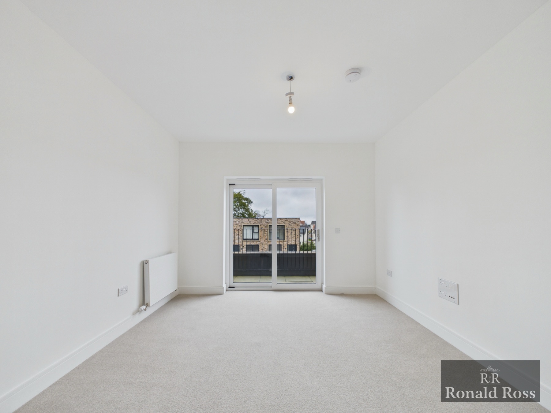 A bright newly decorated living room with balcony doors from a Ronald Ross listing